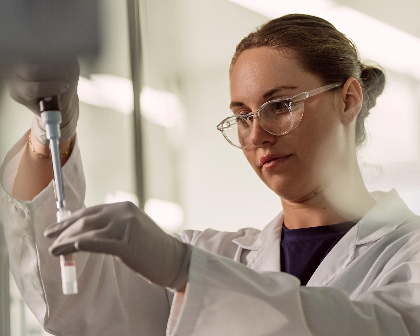 Close up of female scientist holding a single pipette in one hand and a tube in the other.